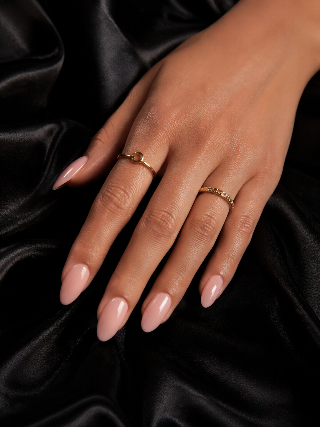 Manicura almendrada en tono rosa nude sobre satén negro